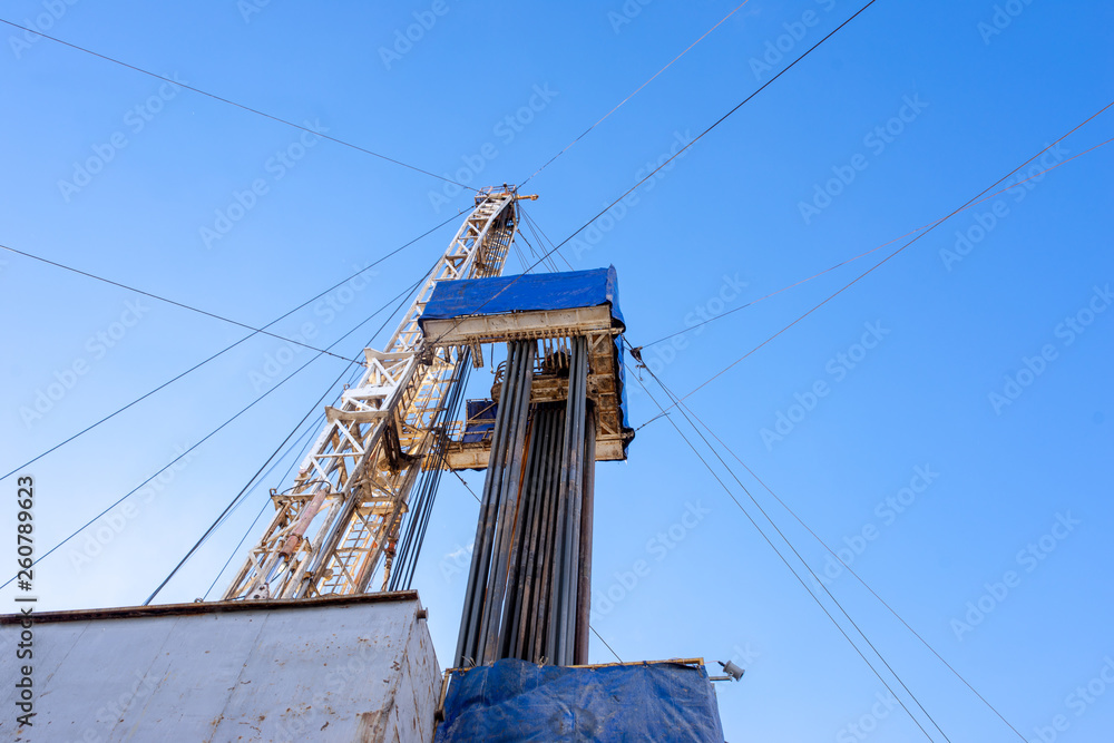 Oil and Gas Drilling Rig onshore dessert with dramatic cloudscape. Oil drilling rig operation on the oil platform in oil and gas industry. Land drilling rig blue sky