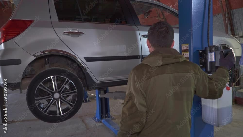 A mechanic raises a car to check on a car lift A mechanic raises a car to check on a car lift
