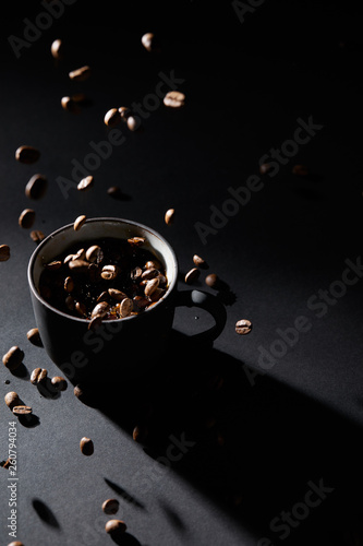 Coffee cup and coffee grains on dark textured surface