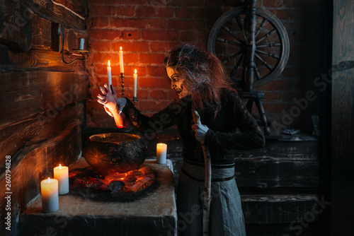 Scary witch reads spell over the pot, seance photo