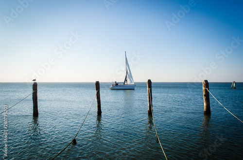 Una barca a vela naviga davanti a Pellestrina, isola della laguna di Venezia in una giornata invernale  photo