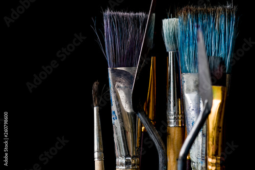 A tool for the artist's work. Several brushes and two spatulas on a black background. Brushes and spatulas have different sizes. Copy space. photo