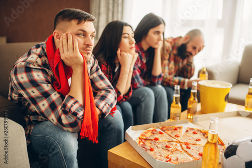 Sad friends watching TV at the boring house party