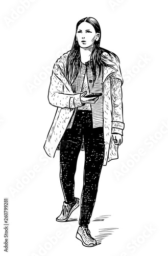 A casual girl with a mobile phone goes down the street