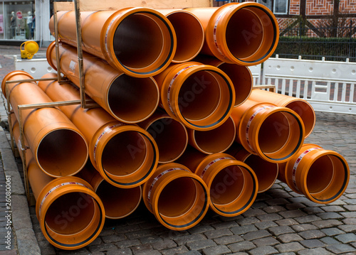 orange PVC pipes stacked in construction site
