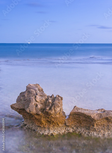 view of a marine rock whipped by the tide at twilight and at the blue hour