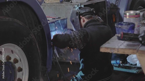 A car mechanic welds a large truck cab photo