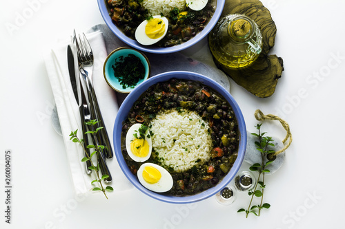 rice with black beans and boiled egg on the table with spices and olive oil. healthy caribbean food