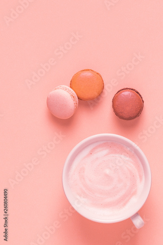 Cup of coffee with macaroons on pastel background.