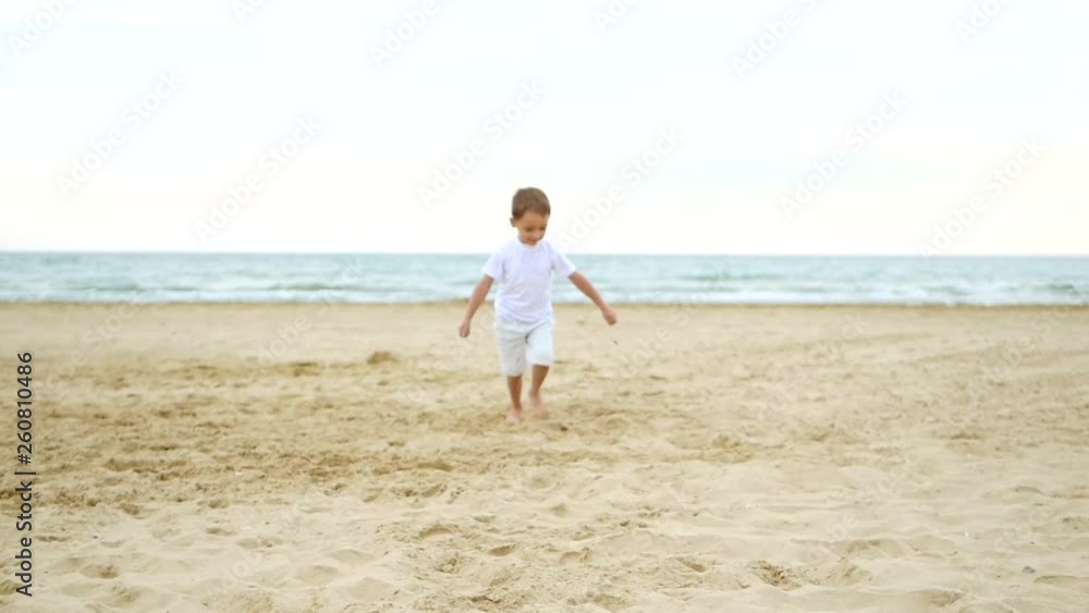 Happy child running along a sandy beach in slow motion. Slow motion. Happy child running along a sandy beach in slow motion. Slow motion.