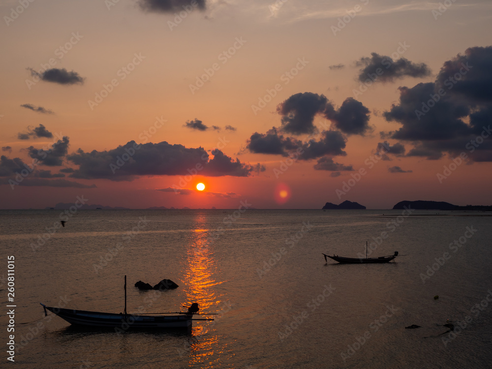 Silhouette of a boat on the background of the setting sun with clouds. Koh Phangan Thailand