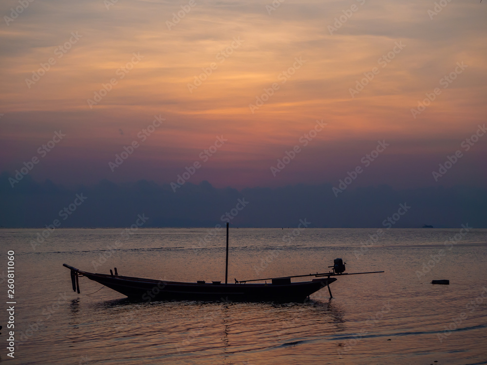 Silhouette of a boat on the background of the setting sun with clouds. Koh Phangan Thailand