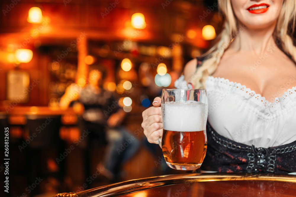 Large breasted waitress holds mug of fresh beer Large breasted waitress holds mug of fresh beer