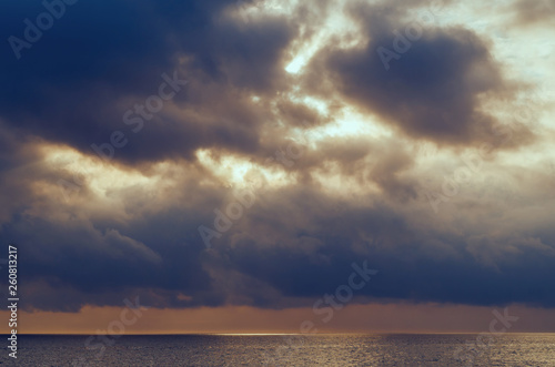 Dramatic storm clouds above the ocean. Gloomy glow on a rainy day. 