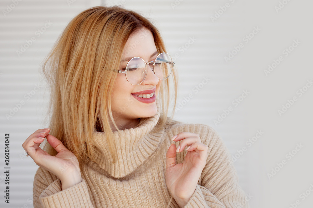 Stylish and beautiful young blonde in beige oversize sweater. Young woman with glasses Stylish and beautiful young blonde in beige oversize sweater. Young woman with glasses