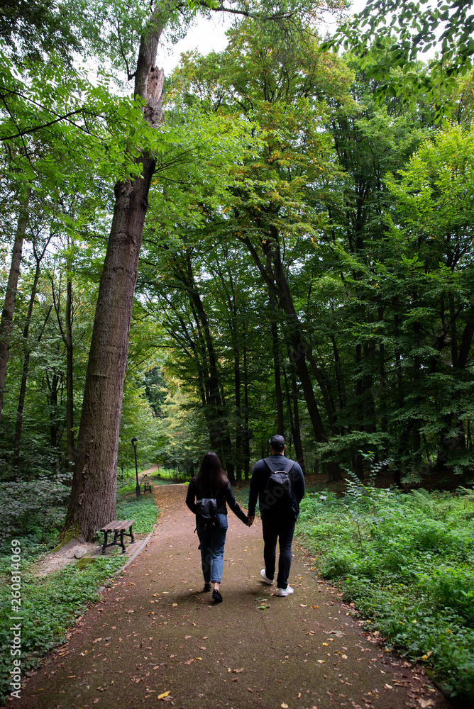 young couple walking by city park holding hands young couple walking by city park holding hands