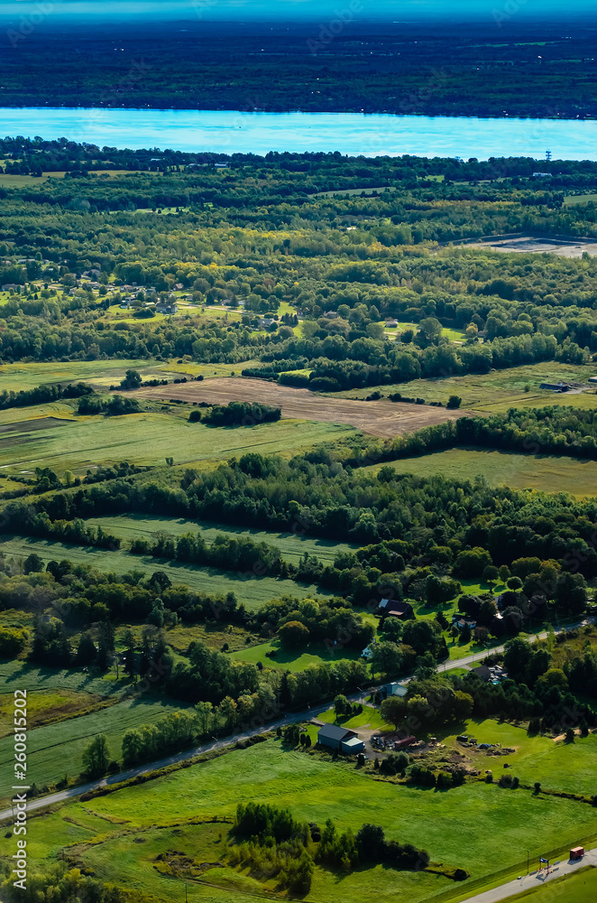 Fototapeta premium Aerial view of farmland with a town and river in the distance