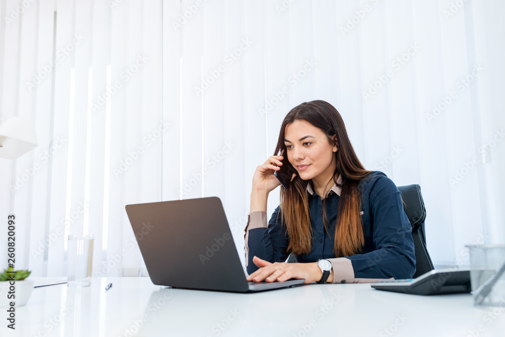 Pretty woman sitting in her office having a business talk over the phone. Pretty woman sitting in her office having a business talk over the phone.