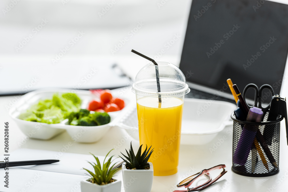 orange juice and green plants near tasty vegetables and laptop with blank screen