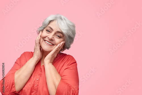 Cheerful senior lady with hands near cheeks