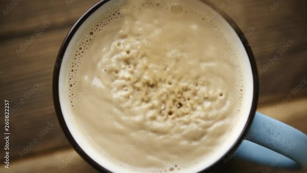 SLow motion shot of pour cane sugar from spoon into cup of coffee with milk SLow motion shot of pour cane sugar from spoon into cup of coffee with milk