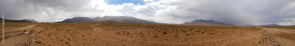 Desert landscape of the Andean plateau of Bolivia with peaks of snow-capped volcanoes of the Andean cordillera