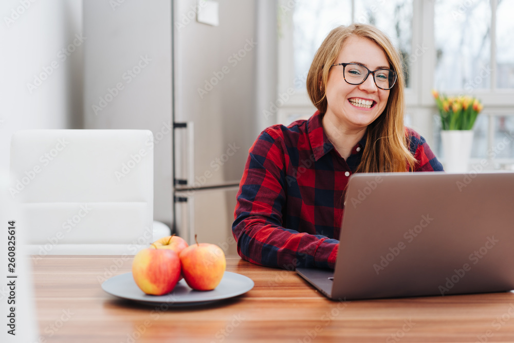 Young woman sitting working on a laptop at home Young woman sitting working on a laptop at home