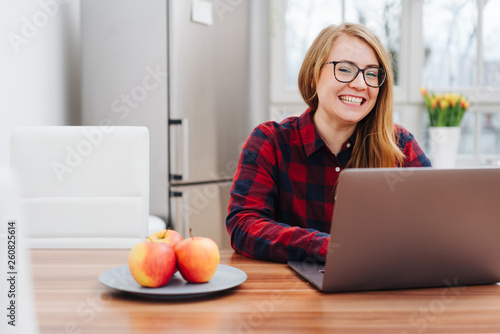 Young woman sitting working on a laptop at home © contrastwerkstatt