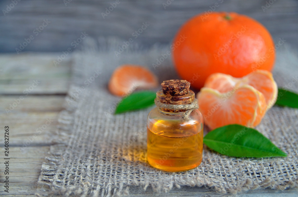 Tangerine essential oil in a glass bottle with fresh fruits on old wooden table. Ripe orange mandarin with leaves and citrus organic oil for spa,skin care, massage and aromatherapy.Selective focus. Tangerine essential oil in a glass bottle with fresh fruits on old wooden table. Ripe orange mandarin with leaves and citrus organic oil for spa,skin care, massage and aromatherapy.Selective focus.