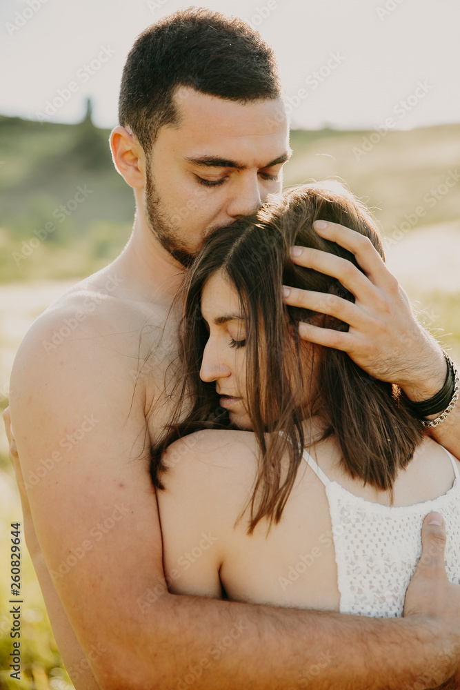 Naklejka premium Stunning brunette hugs naked man and holds her hands on his back