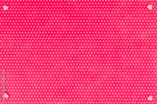 Pink dradge hearts in the corners on the textile background, fuchsia with a print in white polka dots. View from above.