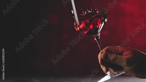 Wine. Red wine pouring in wine glass over dark background. 