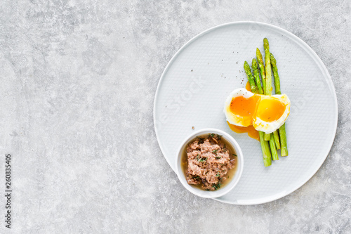 Baked mini asparagus with egg and tuna. Gray background, top view, space for text.