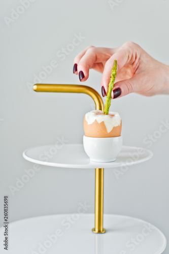 Hand chef inserts a trickle of asparagus in a boiled egg