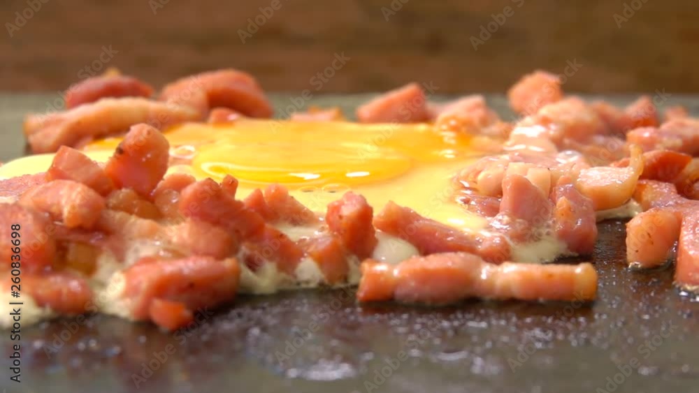 Egg with chopped bacon roasted on the hot surface of the grill. Panoramic camera movement. Egg with chopped bacon roasted on the hot surface of the grill. Panoramic camera movement.