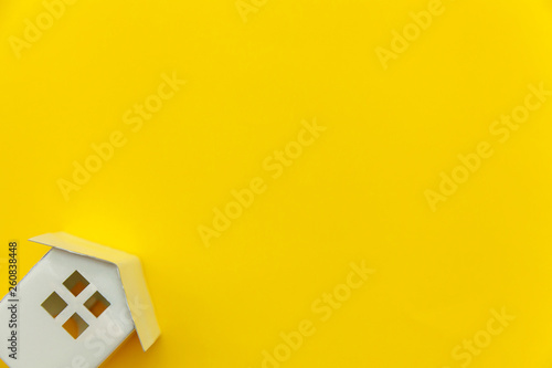 Simply minimal design with miniature white toy house isolated on yellow colourful trendy modern fashion background. Mortgage property insurance dream home concept. Flat lay top view copy space