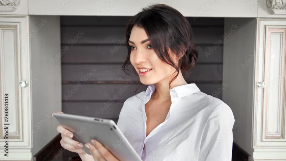Attractive casual woman smiling using tablet PC at vintage kitchen background Attractive casual woman smiling using tablet PC at vintage kitchen background