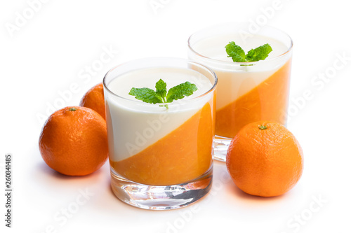 Panna cotta with orange jelly in clear glass isolated on white