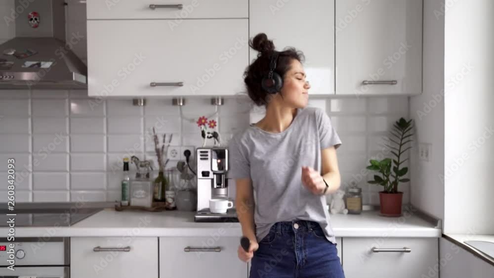 Funny woman housewife dancing and sing with big spoon while cooking in modern kitchen at home Funny woman housewife dancing and sing with big spoon while cooking in modern kitchen at home