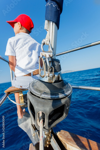 Little boy on board of sailing yacht on summer cruise. Travel adventure, yachting with child on family vacation. photo