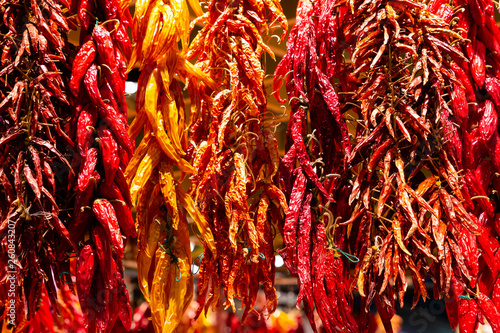 Several varieties of dried hot chili peppers hanging from a open market in Spain. Smoke over heat, and then grind dried chili peppers for blends and rubs or reconstitute in water for salads or salsa.