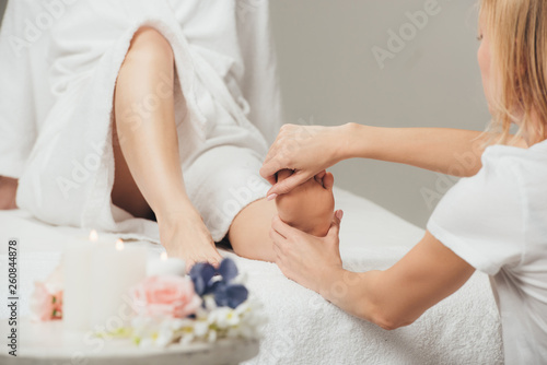cropped view of masseur doing foot massage to adult woman in spa