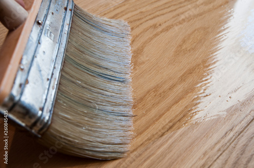 Cuadro en lienzo brush paints the wooden floor with lacquer side view close-up