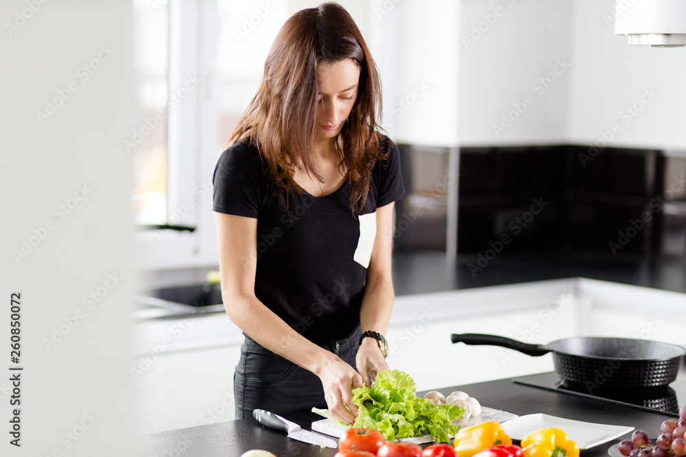 Sporty young woman is preparing healthy food on light kitchen Sporty young woman is preparing healthy food on light kitchen