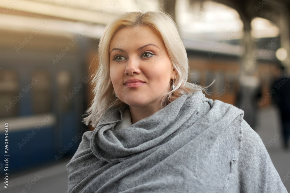 Portrait of a young beautiful European woman on the background of the train at the station. A woman is waiting for the arrival or departure of the train. Travelling by train. trip to Europe. Portrait of a young beautiful European woman on the background of the train at the station. A woman is waiting for the arrival or departure of the train. Travelling by train. trip to Europe.