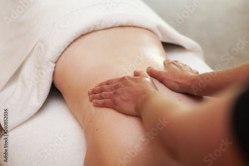 Woman receiving a deep tissue back massage by a masseur on a massage table covered by a white towel