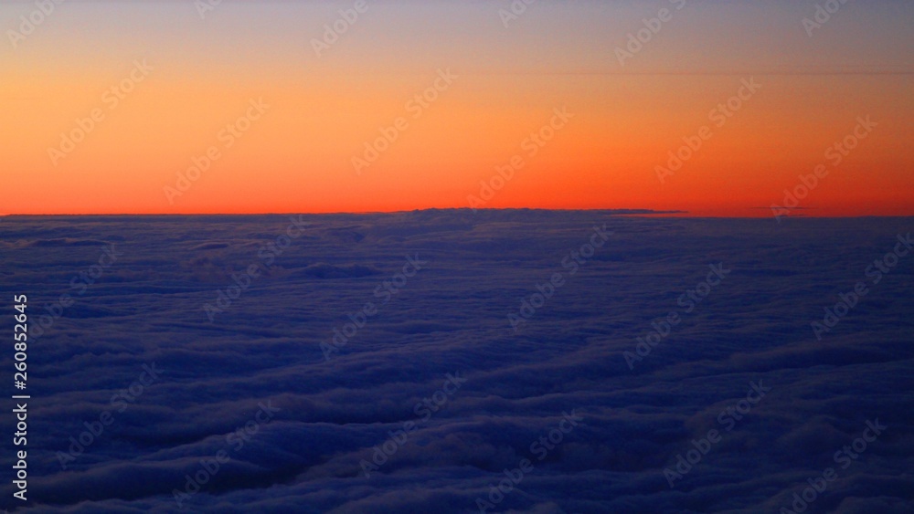 Sunrise from the airplane, high above clouds