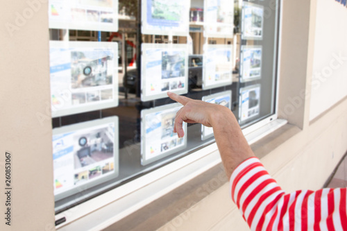 woman hand looks at the window of a real estate agency in the street