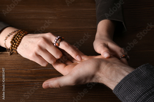 Chiromancer reading lines on man's palm at table, closeup