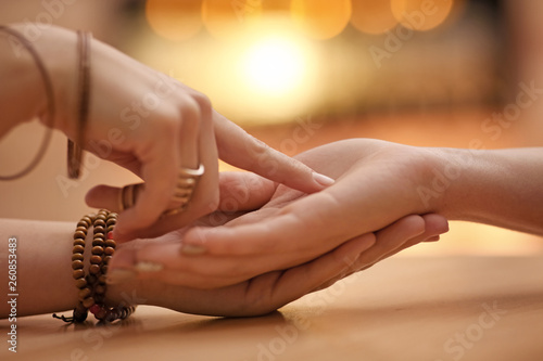 Chiromancer reading lines on woman's palm at table, closeup photo